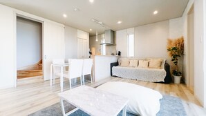 Um espaço de estar moderno e integrado, com área de jantar, sofá e cozinha ao fundo.