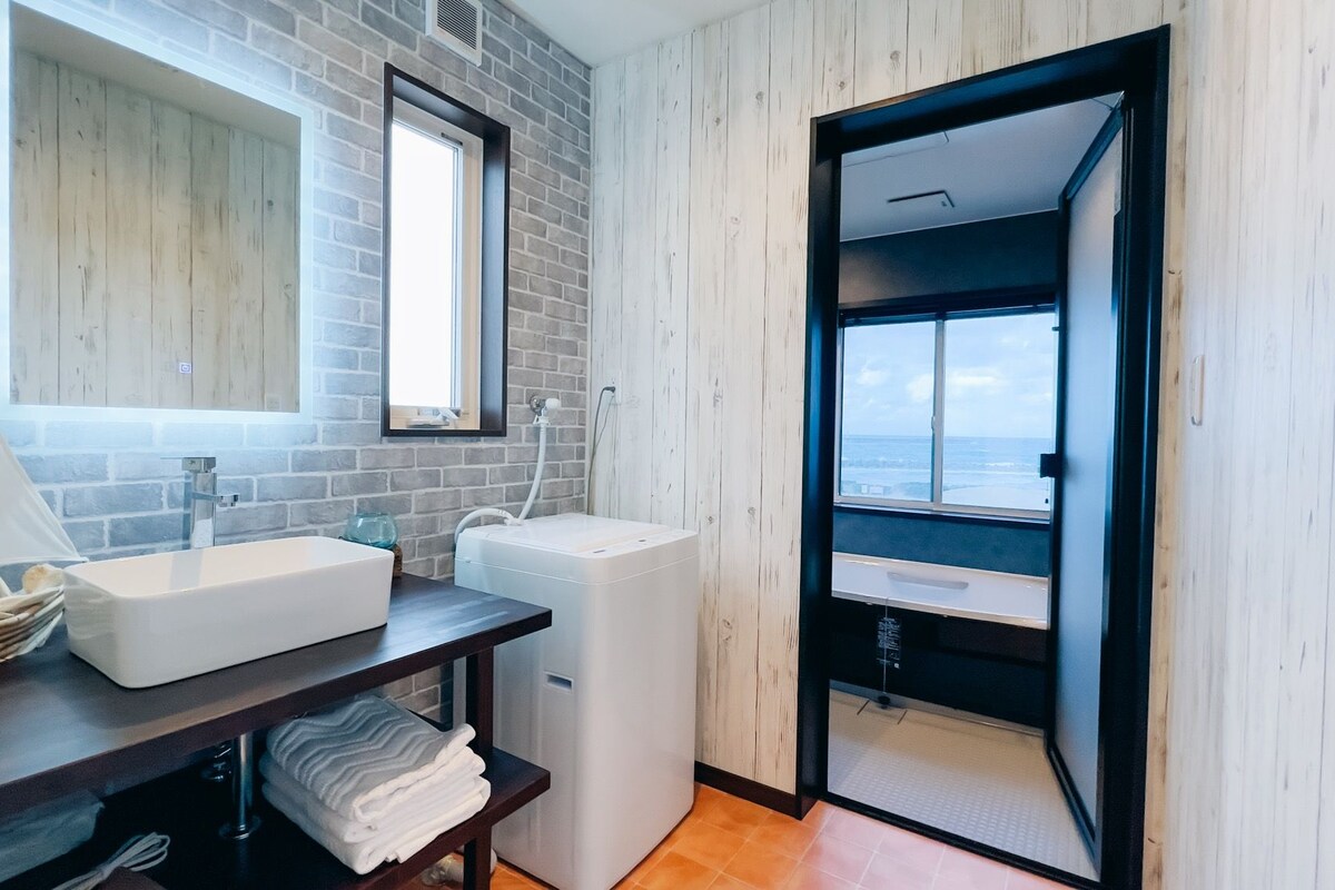 A modern bathroom with a large white sink, a compact toilet, and a shower area.