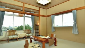 Een traditionele Japanse kamer met tatami vloerbedekking, een lage houten tafel en een groot raam met gordijnen.