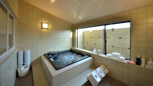 Een moderne badkamer met een groot bad, een raam met uitzicht en een plank met toiletartikelen.