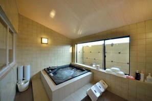 Ein modernes Badezimmer mit einer großen Badewanne, einem Fenster mit Aussicht und Ablage für Toilettenartikel.
