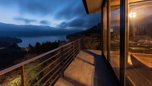 Een balkon met uitzicht op een meer en bergen in de schemering.