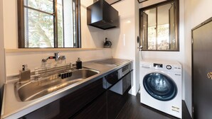 Een moderne keuken met een roestvrijstalen spoelbak, een ingebouwde wasmachine en een raam met zonwering.