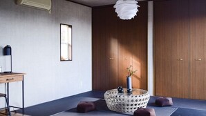 Une pièce avec une armoire en bois, une petite fenêtre, un bureau avec une lampe et un panier décoratif contenant un vase.