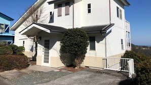 Un bâtiment à deux étages, doté d’un toit plat, d’un petit porche et d’une entrée fermée par un portail.