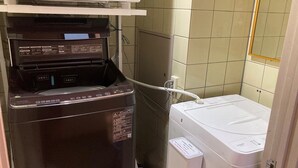 A compact laundry area with a washing machine and a dryer. - Sanda Sunrise Hotel (Sanda)