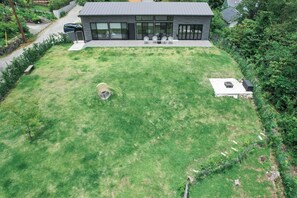 A modern house with a large lawn, a patio area with seating, and a small outdoor kitchen. - Villa Doggo Izu (Ito)