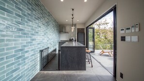 Een moderne keuken met een centraal eiland, een blauwe tegelachtergrond en een groot raam met uitzicht op de omgeving.