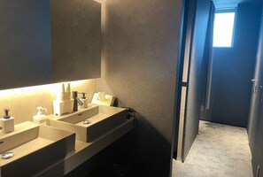 A modern bathroom with two sinks, a mirror, and a window providing natural light. - Sauna Stay (Setouchi)