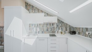 Una cocina moderna con armarios blancos, salpicadero de azulejos y un tragaluz.