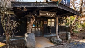Ein traditionelles japanisches Gebäude mit Holzfassade, einem gefliesten Eingang und einem Schild.