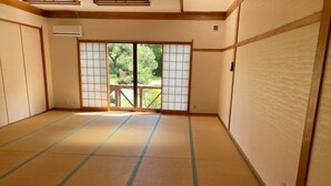 A tatami mat room with sliding doors, a view of greenery outside, and a wooden ceiling. - Tabito Auto Camp Tabitoso (Iwaki)
