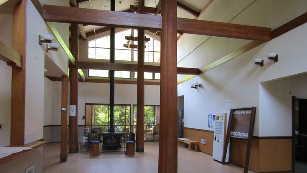 A spacious hall with high ceilings and wooden beams, large windows allowing natural light, and a central area with a fireplace. - Tabito Auto Camp Tabitoso (Iwaki)