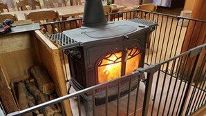 A wood-burning stove with logs stored nearby, enclosed by a metal fence. - Tabito Auto Camp Tabitoso (Iwaki)