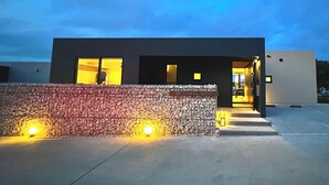A modern building with a stone wall entrance, a visible reception area, and a clear sky. - The 478 Pool & Spa Miyakojima Luxury Villa (Miyakojima)