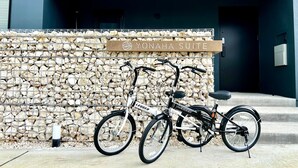 A bicycle parked in front of a stone wall with a sign reading "YONAHASUITE". - The 478 Pool & Spa Miyakojima Luxury Villa (Miyakojima)