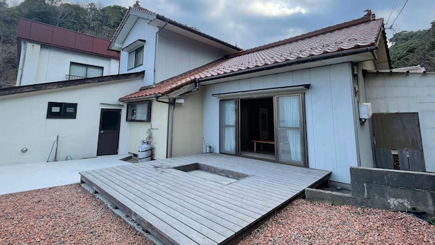 A two-story building with a tiled roof, a wooden deck, and a small outdoor area with gravel. - Kanaso (Hamada)