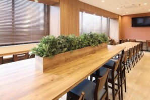 A conference room with a long wooden table, multiple chairs, and a row of potted plants. - AB Hotel Konan (Konan)