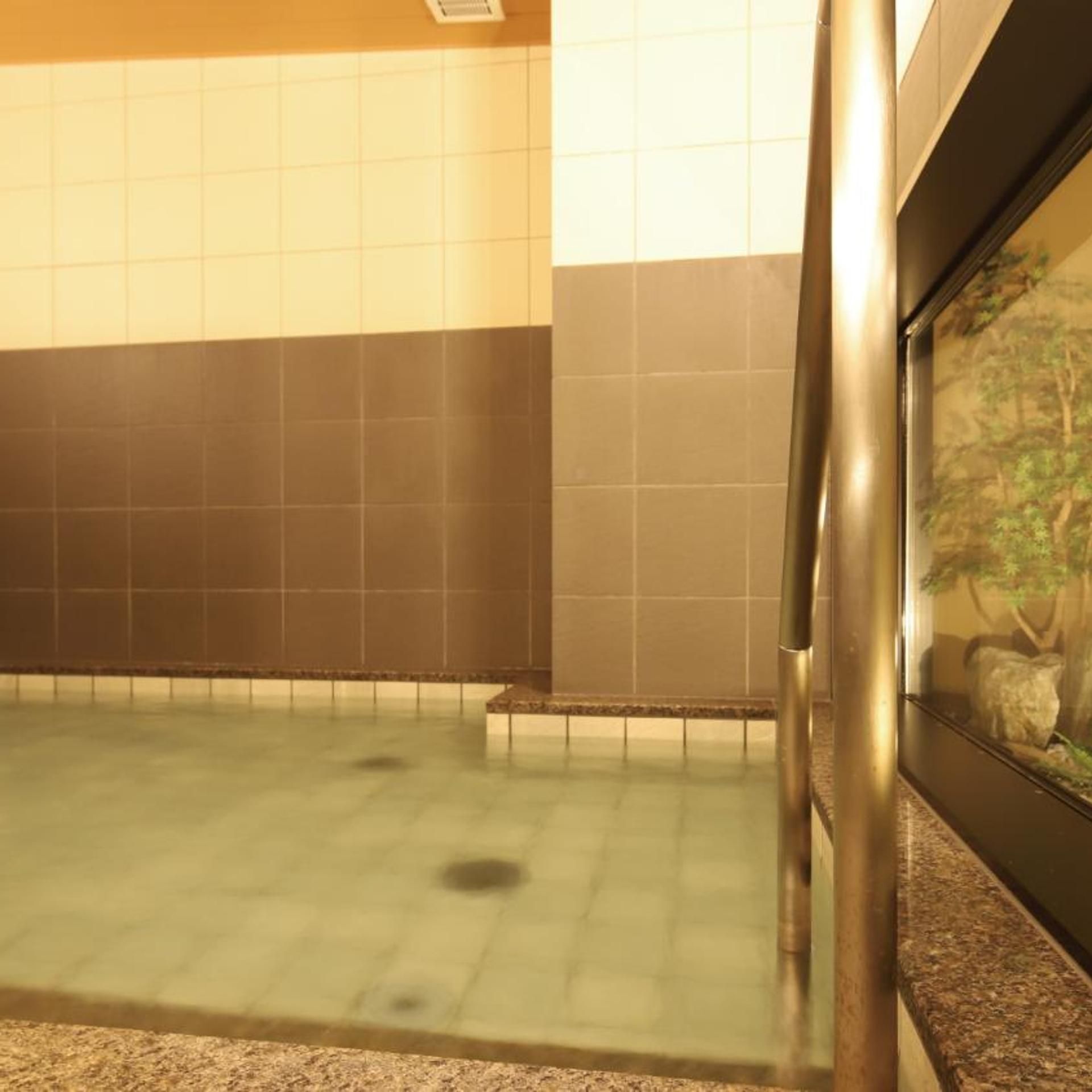 Un baño con piso de baldosas, encimera de granito y lavamanos instalado en la pared.
