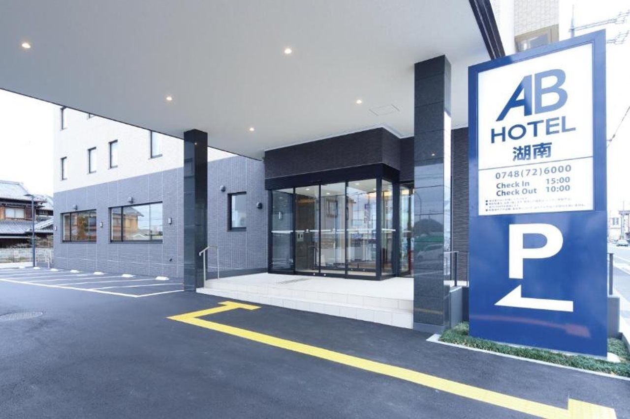 En moderne hotelindgang med glasfacade, parkeringsskilt og tidsplan for ind- og udtjekning.