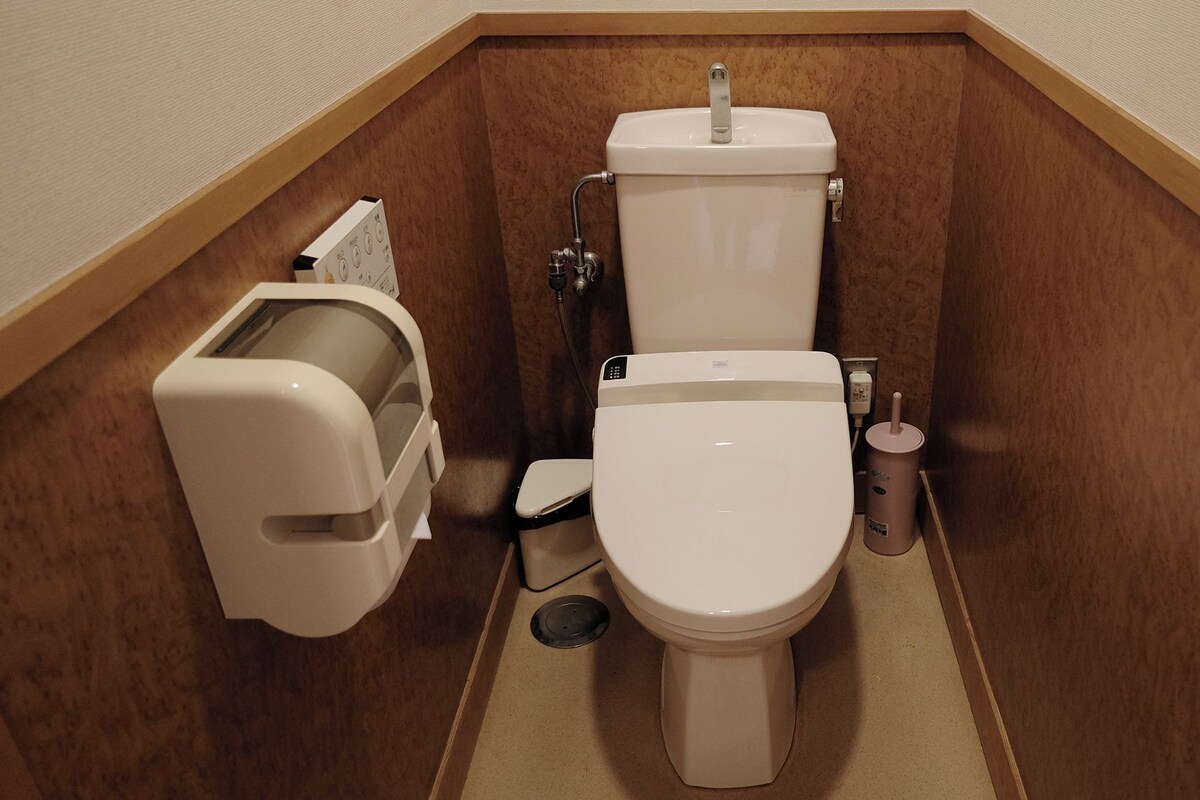 A compact bathroom with a toilet, bidet, and a trash bin.