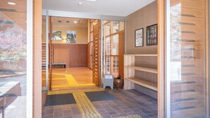 A hotel lobby with a reception desk, wooden panel walls, and a tiled floor.
