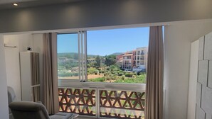Una stanza moderna con un'ampia finestra, un divano, un tavolino e vista su una zona residenziale.