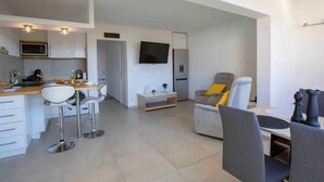 Un soggiorno moderno con cucina, zona pranzo e TV a parete.