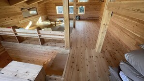 Een houten hutje met een schuin dak, ingebouwde banken en een kleine tafel.