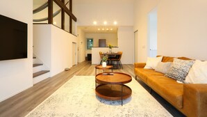 Un salon moderne avec un canapé marron, une table basse ronde et un escalier.