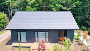 Une maison moderne à deux étages, dotée d’un toit plat, de grandes fenêtres et d’un petit porche.