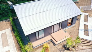 A modern house with a sloped roof, large windows, and a patio area. - Albatross Karuizawa (Karuizawa)