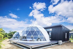 Two geodesic dome structures with a flat roof, connected to a wooden building with a dark exterior. - The Glamping Plaza Ise-shima Base (Shima)