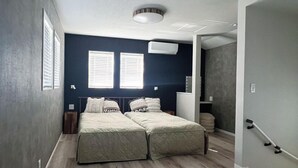 A bedroom with two beds, a ceiling light, and a window with blinds. - Namihara Secret (Minamiboso)