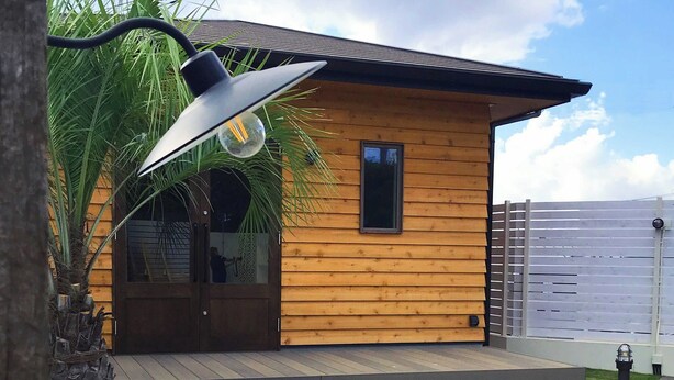 A modern wooden cabin with a deck, outdoor seating, and a sink. - Namihara Secret (Minamiboso)