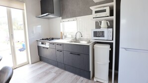 A modern kitchen with a built-in stove, microwave, and sink. - Namihara Secret (Minamiboso)