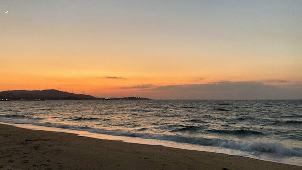 Una playa con olas y un atardecer.
