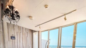 Een moderne woonkamer met een grote schuifpui naar een balkon met uitzicht op zee.