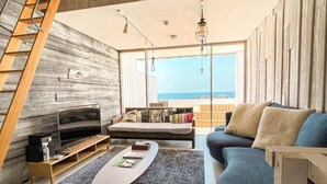 Een moderne woonkamer met een grote televisie, bank en uitzicht op de oceaan.