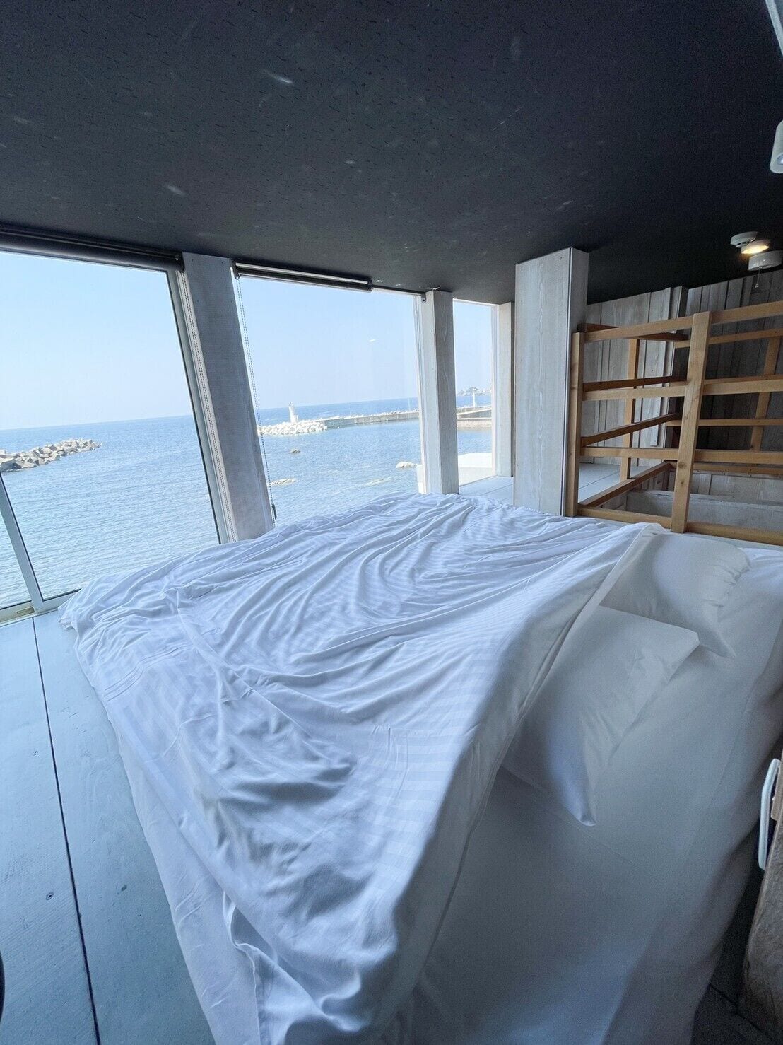 Une chambre avec une grande fenêtre donnant sur un plan d’eau et une jetée.