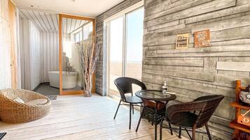 A modern interior with a wooden floor, a dining area with chairs and a table, and a view of the outside.