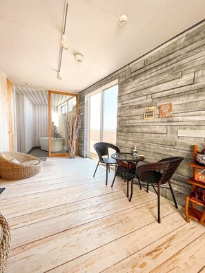 Un interior moderno con suelo de madera, un área de comedor con sillas y una mesa, y vistas al exterior.