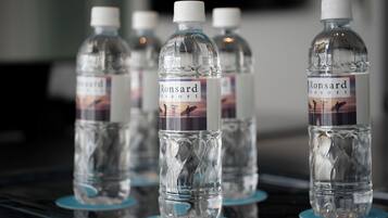 Varias botellas de agua con la etiqueta 'Ronsard Resort' sobre una superficie reflectante.