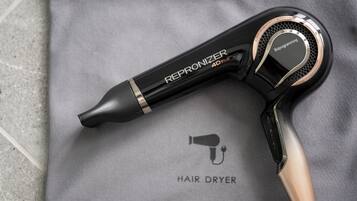 Un secador de pelo con la etiqueta 'REPRONIZER 4D PLUS' sobre una superficie de tela gris.