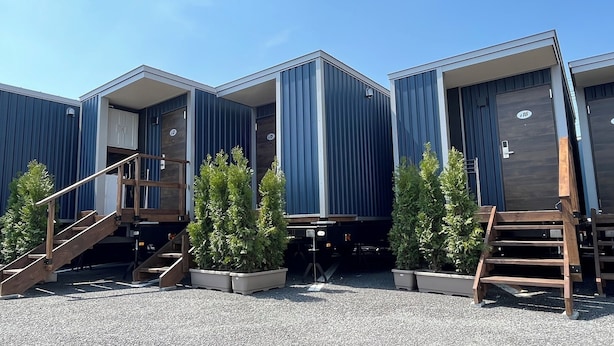 A row of modern, blue modular buildings with wooden staircases and potted plants. - Trail inn Akitakou (Akita)