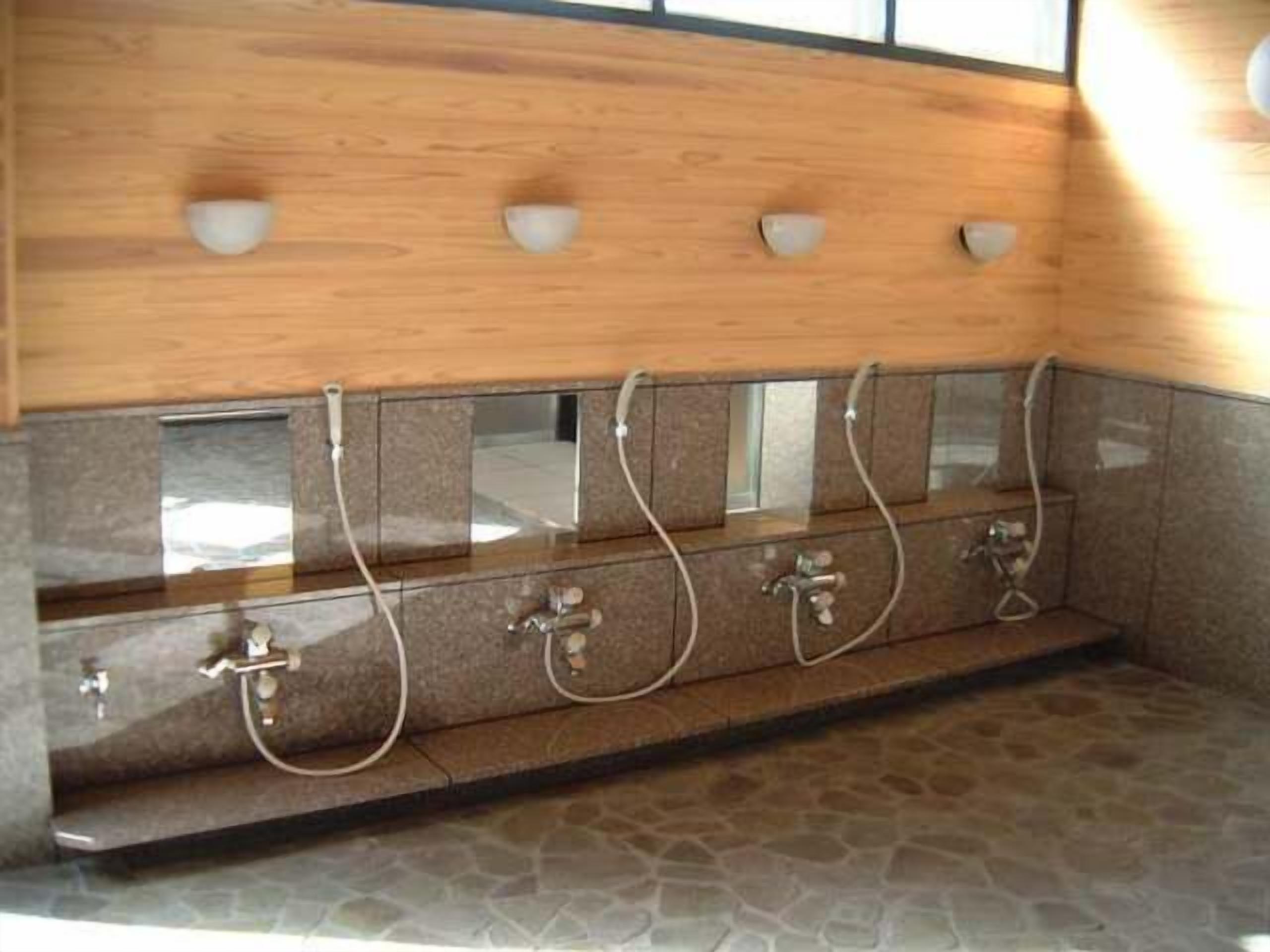 A public shower area with multiple showerheads and a wooden panel above.