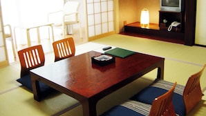 Une pièce de style japonais traditionnel, avec un sol recouvert de tatamis, une basse table en bois et des chaises en bois.