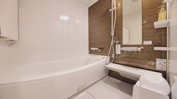 A modern bathroom with a white bathtub, a wooden accent wall, and a built-in sink.