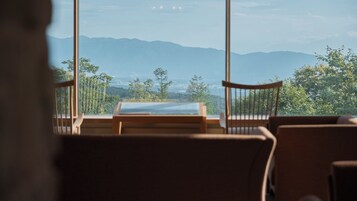 A room with a large window offering a view of mountains and trees.