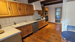 Una cucina con mobili in legno, lavastoviglie, lavello e una sedia blu.